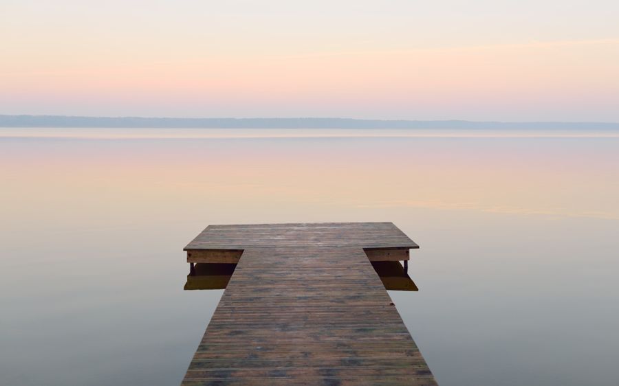 Wooden dock reaching into a calm, misty lake at dawn